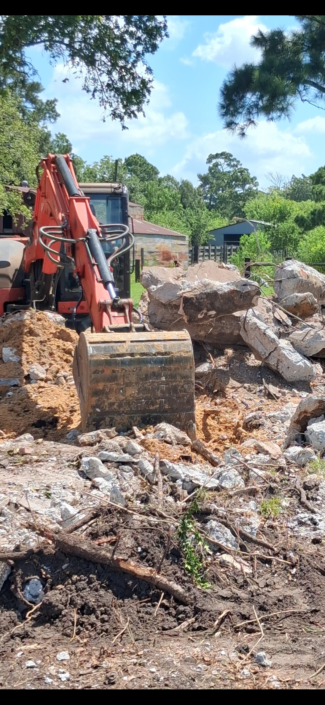 Excavator breaking and removing concrete rubble on Texas job site