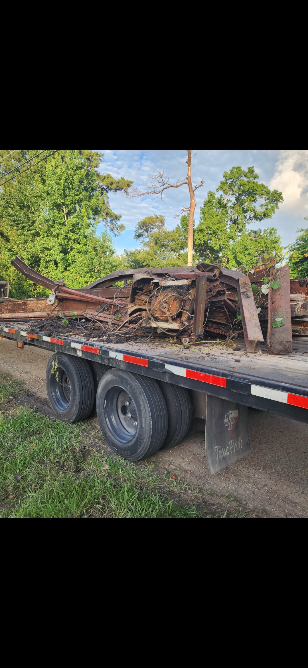 Wrecked vehicle frame loaded on flatbed trailer for haul-off in Texas